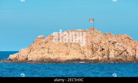 Seascape mit kleinen felsigen Insel im Mittelmeer, auf dem Flagge von Katalonien gesetzt ist. Tossa de Mar, Costa Brava. Stockfoto
