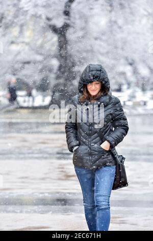 Sliven, Bulgarien - März 22nd 2018: Junge lächelnde Frau, die unter dem fallenden Schnee läuft Stockfoto