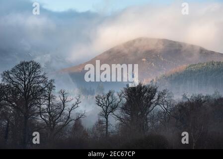 Episches Landschaftsbild mit Blick über Derwentwater im Lake District Catbells schneebedeckter Berg mit dichtem Nebel Rollen durch Tal Stockfoto