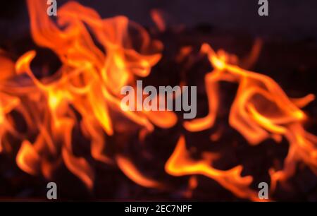 Orangenfeuer auf Mangel Kohle. Abstraktes, unscharrides Foto für den Hintergrund. Verschwommene Kamintapete. Vorlage für Banner mit brennendem Feuer. Sicherheit für Zuhause und Anti-Fi Stockfoto