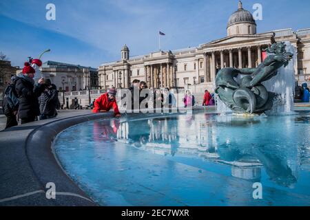 London, Großbritannien. Februar 2021, 13th. Als der Sturm Darcy verblasst und das Eis zu schmelzen beginnt, kommen die Menschen heraus, um das letzte Eis auf den Statuen auf dem Trafalgar Square zu sehen. Besucher treffen sich mit Freunden und/oder trainieren. Outdoor-Leben im Zentrum von London in Lockdown 3. Kredit: Guy Bell/Alamy Live Nachrichten Stockfoto