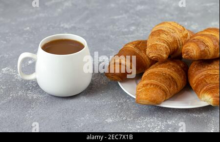 Frisch gebackene Croissants und eine Tasse Kaffee auf rustikalem Stein Tabelle Stockfoto