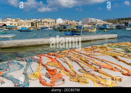 Traditionelle bunte maltesische Fischernetze auf Beton Pier. Fischernetze zum Trocknen in Marshallock oder Marsaxlokk, berühmt als Fischerdorf in Mal Stockfoto