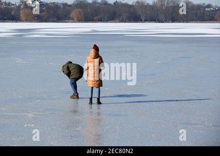 13. Februar 2021, Hamburg: Auf dem Eis der Außenalster in der Sonne sind die Menschen unterwegs. Im Laufe des Tages hat die Hamburger Polizei immer wieder Leute aus der Außenalster geholt, weil das Eis der Alster noch zu dünn ist und nicht zum Laufen geräumt wurde. Foto: Bodo Marks/dpa Stockfoto