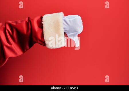 Hand eines Mannes trägt weihnachtsmann Kostüm und Handschuhe über rotem Hintergrund tut Daumen nach unten Ablehnung Geste, Ablehnung Abneigung und negatives Zeichen Stockfoto