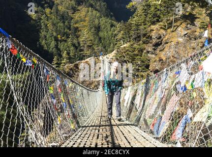 Glückliche Wanderin auf einer Hängebrücke in Nepal, Everest Base Camp Trek, auf dem Weg nach Namche Bazar, Trekking im Himalaya Gebirge Stockfoto