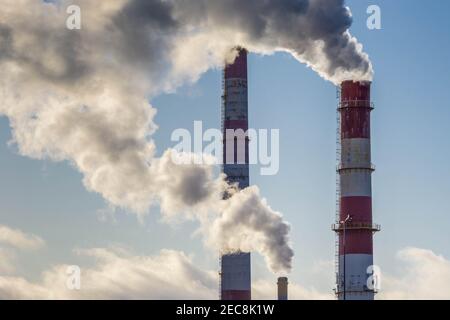 Dicker Rauch aus drei Fabrikschornsteinen. Werksrohre mit Rauch auf blauem Himmel Hintergrund. Globale Erwärmung. Luftverschmutzung. Kopierbereich, horizontal Stockfoto