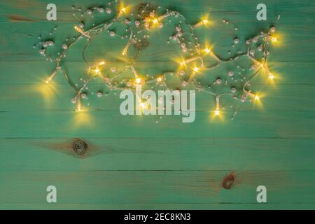 Weihnachtsbeleuchtung Dekoration über Holz vintage grün lackierten Hintergrund. Leuchtende Girlande im Hintergrund. Speicherplatz kopieren Stockfoto