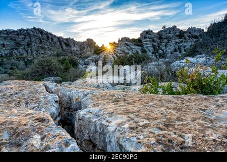 Landschaft mit Abendlicht mit einem Sonnenstern im El Torcal Naturschutzgebiet in Andalusien mit seltsamen Karstfelsen Formationen Stockfoto