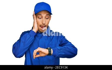 Glatze Mann mit Bart tragen Baumeister Jumpsuit Uniform Blick auf die Uhr Zeit besorgt, Angst, zu spät Stockfoto
