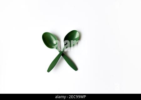 Zwei grüne Plastiklöffel auf weißem Hintergrund. Umweltproblem, Umweltverschmutzung. Stockfoto