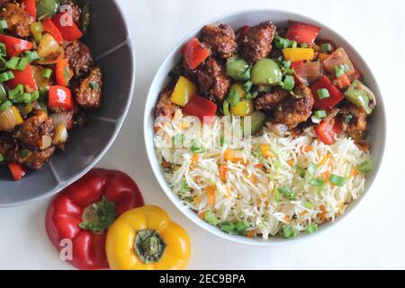 Gemüsekarotte gebratener Reis mit indischen Gewürzen serviert zusammen mit kühlem Huhn. Hausgemachte Speisen auf weißem Hintergrund aufgenommen Stockfoto