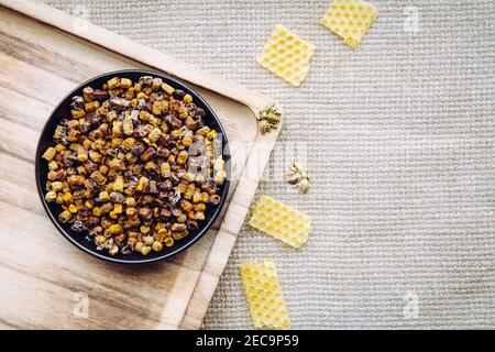 Alternative Medizin Bienenbrot (fermentierte Blumen und Pflanzenpollen von Honigbienen) Pellets auf Teller. Bienenwachs Cera alba und Bienenfiguren zur Dekoration Stockfoto