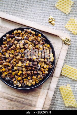 Alternative Medizin Bienenbrot (fermentierte Blumen und Pflanzenpollen von Honigbienen) Pellets auf Teller. Bienenwachs Cera alba und Bienenfiguren zur Dekoration Stockfoto