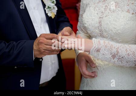 Flacher Fokus des Bräutigams setzen einen Ring auf die Der Finger der Braut während der Trauung Stockfoto