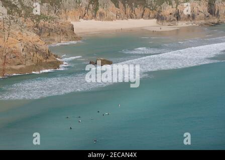 Warten auf große Brandung in Porthcurno Cove; Pedn Vounder Strand in der Ferne. Pedn Vounder ist ein inoffizieller FKK-Strand. Penwith Peninsula, Cornwall. Stockfoto