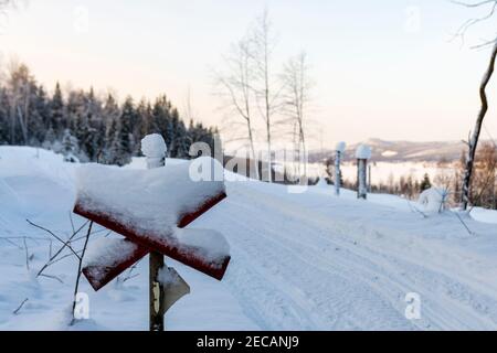 Schild markiert einen Schneemobilweg im Vordergrund und unscharf im Hintergrund ein Blick auf die Landschaft, Bild aus Vasternorrland Schweden. Stockfoto