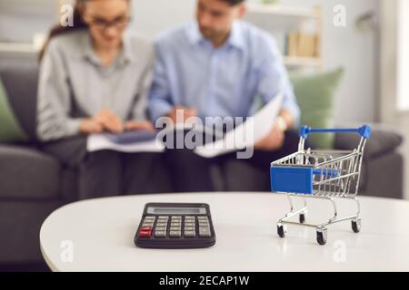 Taschenrechner und Einkaufswagen aus der Nähe, paar Rechenkosten im Hintergrund Stockfoto