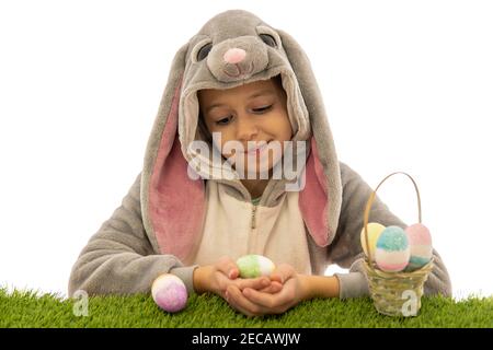 Mädchen im Hase Kostüm Blick auf Osterei auf grünem Gras. Isoliert auf weiß. osterfeiertagskonzept Stockfoto