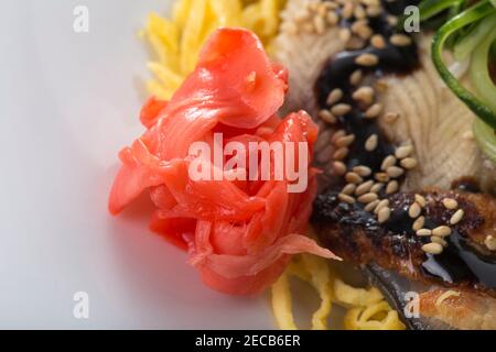 Fischfilets mit Gurkenscheiben und Omelette im asiatischen Stil. Konzentrieren Sie sich auf marinierten Ingwer. Makro. Foto kann als ganzer Hintergrund verwendet werden. Stockfoto
