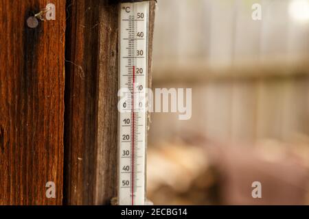 Ein Straßenthermometer hängt an der Wand eines Holzhauses. Stockfoto