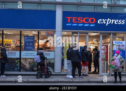 Dublin, Irland. Februar 2021, 12th. Eine Schlange von Menschen vor dem Tesco Express Supermarkt im Stadtzentrum von Dublin während der COVID-19 Pandemiesperre gesehen.Level 5 Sperrbeschränkungen werden von der irischen Regierung um mindestens weitere sechs Wochen verlängert werden, wobei nur Schulen und der Bausektor voraussichtlich vor Ostern wieder geöffnet werden dürfen. Quelle: Cezary Kowalski/SOPA Images/ZUMA Wire/Alamy Live News Stockfoto