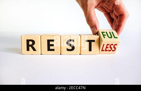Symbol „Restless“ oder „RESTful“. Geschäftsmann dreht den Holzwürfel, ändert das Wort "stlos" in "stful". Schöner weißer Tisch, weißer Hintergrund, Kopie Stockfoto