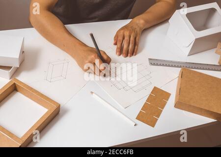 Designer zeichnet ein Mockup für Handwerk Karton. Entwicklung des Verpackungsdesigns Skizze. Stockfoto