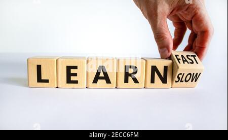 Lernen Sie langsam oder schnell Symbol. Geschäftsmann dreht Holzwürfel und ändert die Worte "langsam lernen" zu "schnell lernen". Schöner weißer Hintergrund, Kopierbereich. Busi Stockfoto