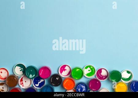Auf dem Tisch sind Acrylfarben verschiedener Farben zum Zeichnen geöffnet. Helle bunte Hintergrund aus Farbdosen Stockfoto