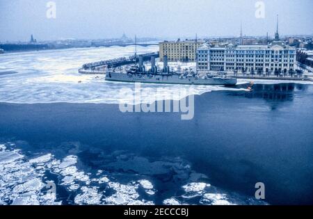 1990 Archivfoto des Cruiser Aurora über den gefrorenen Fluss Bolshaya Nevka und den Fluss Neva in Leningrad, jetzt St. Petersburg, Russland. Stockfoto