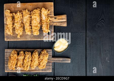 Hausgemachte knusprig gebratene Hühnerteile auf schwarzem Holztisch, flach liegend, mit Kopierplatz. Stockfoto