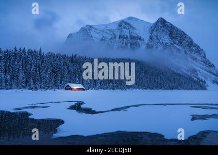 Mitte Januar geht die blaue Stunde am Lake Louise ein, während sich um Mount Fairview im Banff National Park Schneewolken aufwirbeln. Stockfoto