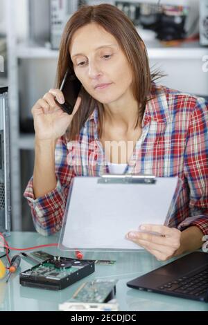 Frau am Telefon, die mit einem Computer arbeitet Stockfoto