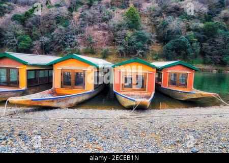 Touristenboote auf dem Katsura-Fluss vor dem Arashiyama-Berg in Kyoto, Japan. Stockfoto