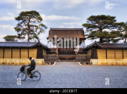 Verschwommener einsamer Fahrradfahrer vor historischen Toren zum alten Kaiserpalast in Kyoto-Stadt Japan. Stockfoto