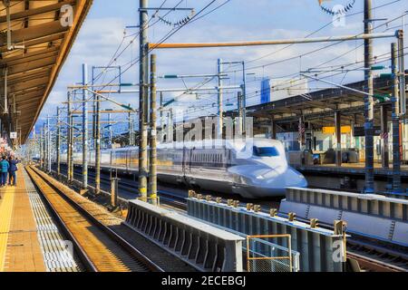 Express-Zug, der Bahnhofsplattformen in Shin-Fuji-Stadt von Japan an einem sonnigen Tag passiert. Stockfoto