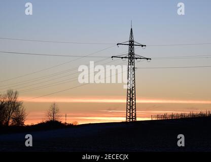 Elektrische Masten silhouetted in der Abenddämmerung, als sie elektrische Energie über das Land transportieren. Sie transportieren Strom. Stockfoto