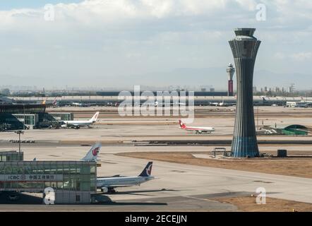 Luftaufnahme verschiedener Flugzeuge, darunter ein Air China Airbus, Und ein Sichuan Airlines Jet geparkt am Gate und auf dem Vorfeld am Terminal 3 , mit seinem Kontrollturm in voller Sicht auf einen sonnigen, blauen Himmel, schadstofffreien Tag am Beijing Capital Airport, im Shunyi Bezirk der chinesischen Hauptstadt, Peking, China, PRC. © Time-Snaps Stockfoto