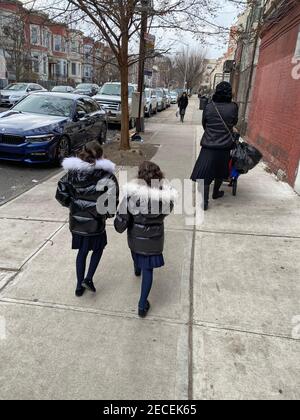 Orthodoxx Jüdische Mutter schiebt Babykutsche vor ältere Schwestern, die im Boro Park Viertel von Brooklyn, New York, zurücklaufen. Stockfoto