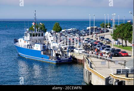 Touristen und Autos warten auf die Fähre Frau Chi-Cheemaun in South Baymouth, MANITOULIN Island, Georgian Bay. USGS-Vermessungsboot Sturgeon ist als Stockfoto