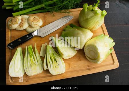 Quartering Fenchel Bulbs auf einem Bamboo Cutting Board: Schneiden Sie vier frische Fenchel-Glühbirnen auf einem Bambus-Schneidebrett Stockfoto