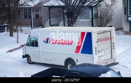 Calgary, Alberta, Kanada. Februar 12 2021. Ein Purolator Lieferwagen außerhalb eines Wohngebietes im Winter. Stockfoto