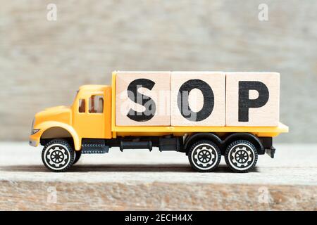 Spielzeug LKW halten Alphabet Buchstaben Block in Wort SOP (Abkürzung Standard Operating Procedure) auf Holzhintergrund Stockfoto