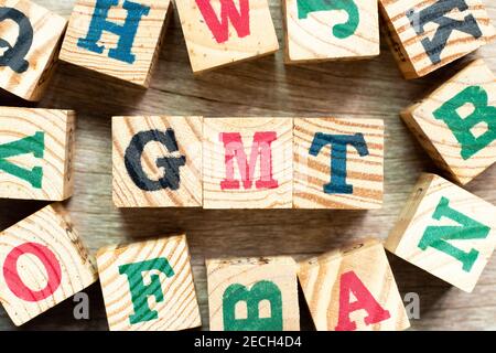 Buchstabenblock im Wort GMT (Abkürzung für Greenwich Mean Time) mit einem anderen auf Holzhintergrund Stockfoto