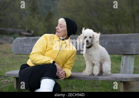 Eine ältere Frau und ihr Pudel genießen die Natur an einem kühlen Frühlingstag. Stockfoto