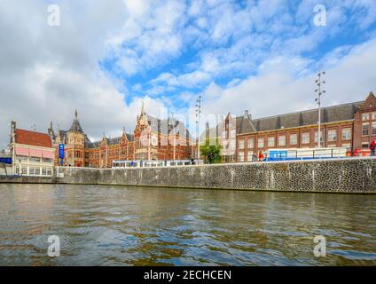 Der Amsterdamer Hauptbahnhof oder Bahnhof von einem Boot auf einem Kanal aus gesehen. Stockfoto