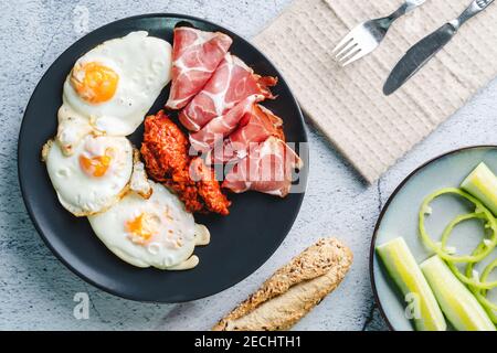 Blick von oben auf die sonnige Seite Eier Prosciutto coppa Capocollo trockenes Fleisch und hausgemachten Ajvar Paprikasalat auf der Tisch als Abendessen oder Frühstück Stockfoto