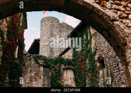 Fassade von alten Steingebäuden in Perouges, rote Fenster, Blumen, Efeu, Frankreich. Hochwertige Fotos Stockfoto