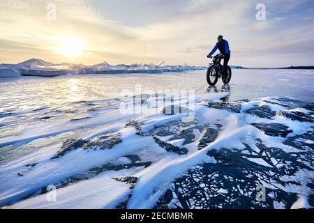 Mann fahren fette Fahrrad am gefrorenen See Kapchagay am Sonnenuntergang In Kasachstan Stockfoto